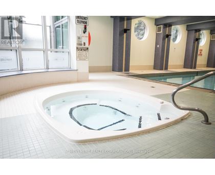 A hot tub in a room with a sign that says "Emergency Telephone".