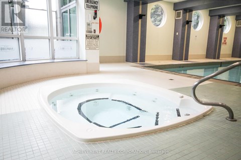 A hot tub in a room with a sign that says "Emergency Telephone".