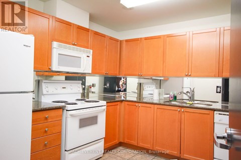 A kitchen with orange cabinets and a white fridge.