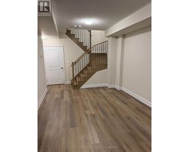A wooden staircase with a metal railing in a white room.