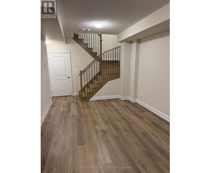 A wooden staircase with a metal railing in a white room.