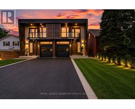 A modern house with a large front yard and a driveway leading to the garage.