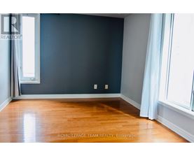 A room with a wooden floor and a window with white curtains.