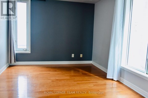 A room with a wooden floor and a window with white curtains.