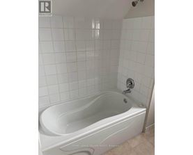 A white bathtub in a bathroom with white tiled walls.