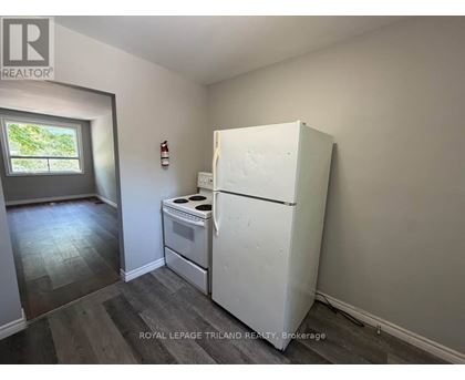 A white refrigerator in a room with a window.