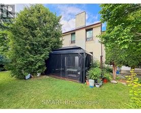 A black screened-in gazebo is in a grassy yard.