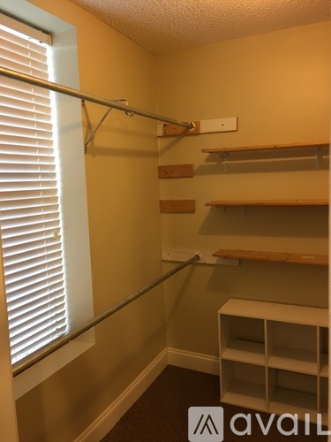 A room with a shelf and a window with blinds.