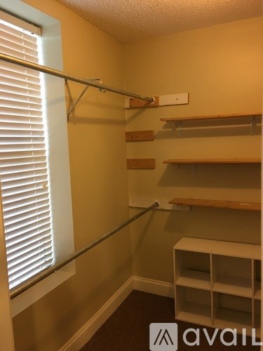 A room with a shelf and a window with blinds.