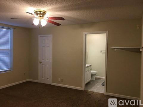 A room with a ceiling fan and a toilet in the bathroom.