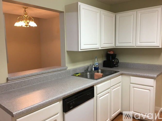 A kitchen with white cabinets and a grey countertop.