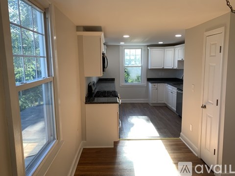 A kitchen with white cabinets and a window with a view of a street.