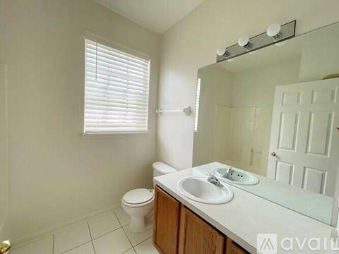 A bathroom with a toilet, sink, and mirror.