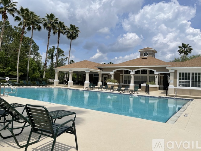 A pool with chairs and a house with a balcony.