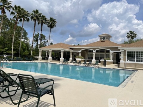 A pool with chairs and a house with a balcony.