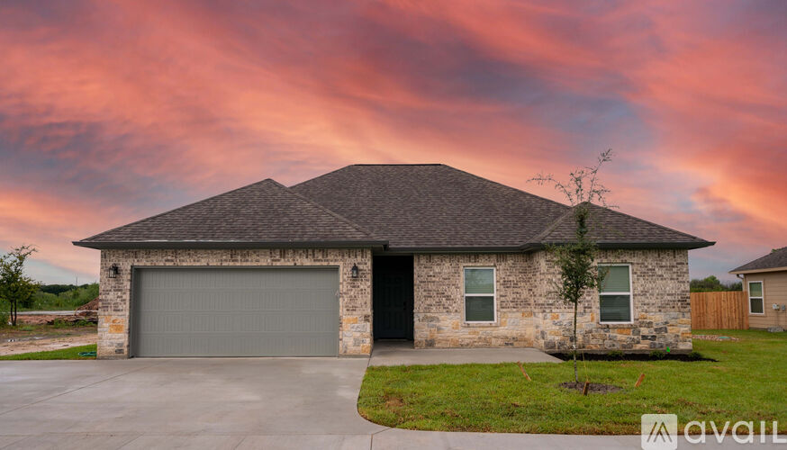 A house with a stone facade and a grey garage door is available for purchase.