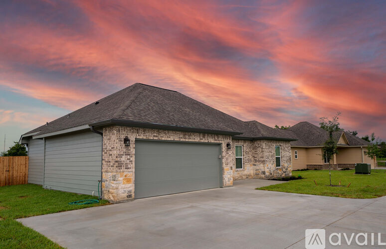 A house with a grey garage door is in front of a pink and blue sky.