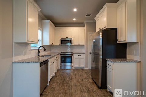 A kitchen with white cabinets and a black refrigerator.
