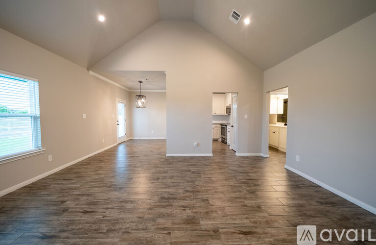 A spacious room with wooden flooring and white walls.