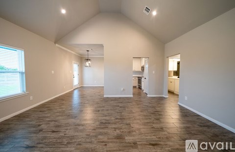 A spacious room with wooden flooring and white walls.