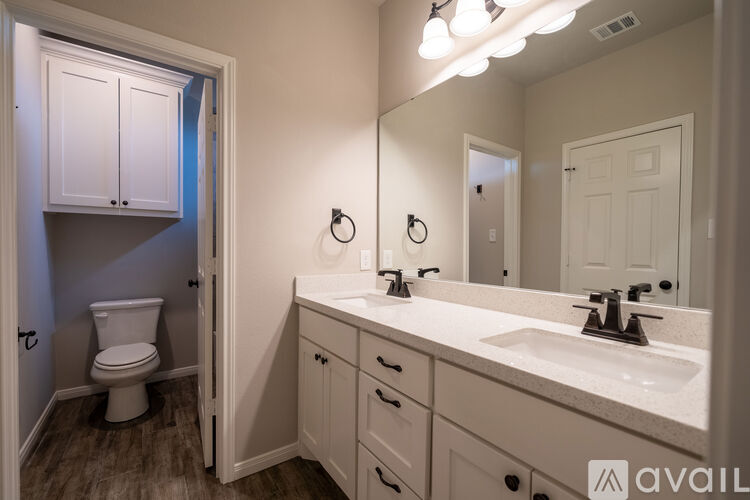 A bathroom with a toilet, sink, and mirror.