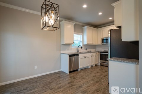 A kitchen with white cabinets and a wooden floor.