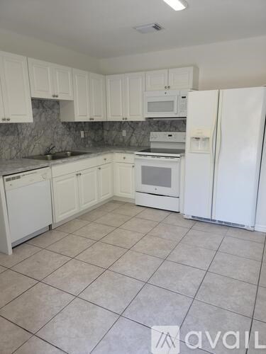 A kitchen with white cabinets and appliances.