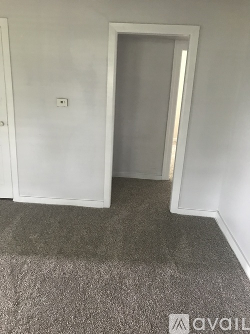 A room with a carpeted floor and a white door.