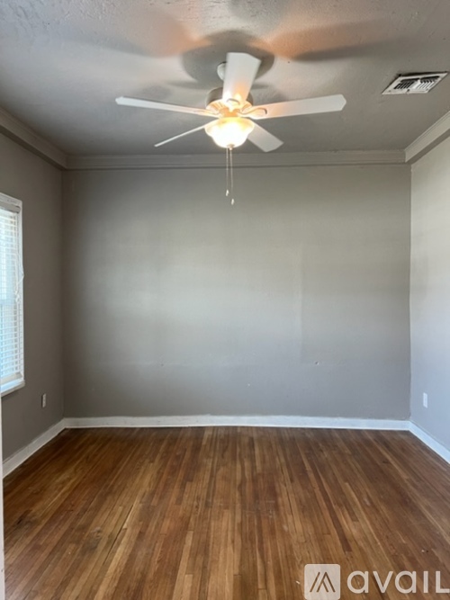 A room with a ceiling fan and wooden flooring.