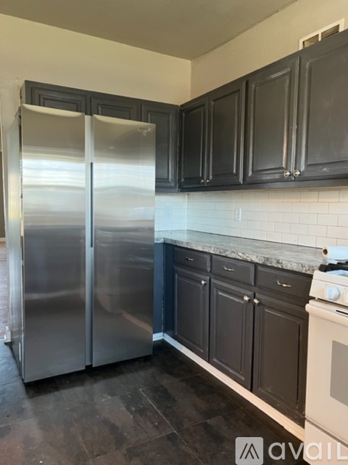 A kitchen with a stainless steel refrigerator and black cabinets.