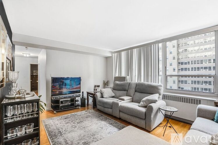 A living room with a grey sofa set, a television, and a glass cabinet.