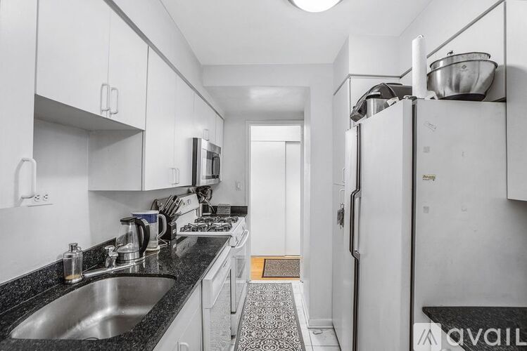 A kitchen with white cabinets and black countertops.