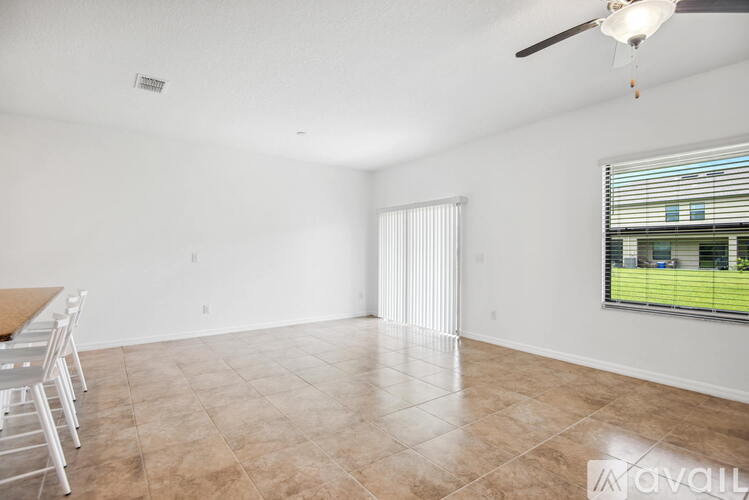 A spacious living room with a ceiling fan and a view of a green lawn through the window.
