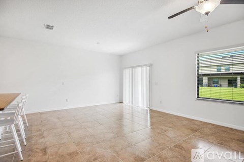 A spacious living room with a ceiling fan and a view of a green lawn through the window.