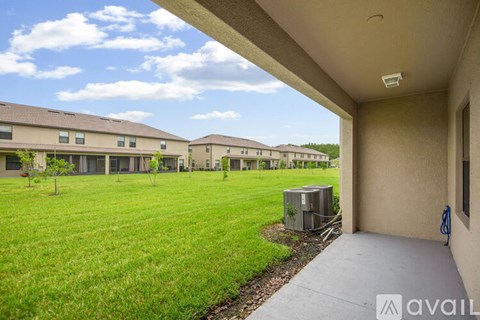 A view of a grassy area with a building in the background and a carport in the foreground.