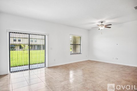A spacious room with a sliding glass door leading to a green outdoor area.