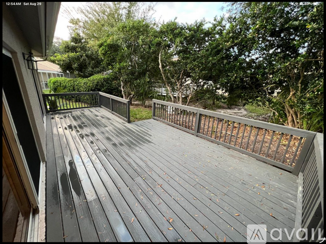 A wooden deck with a railing and trees in the background.