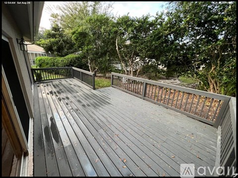A wooden deck with a railing and trees in the background.
