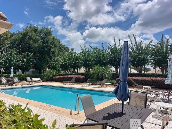 A pool area with a blue umbrella and chairs.