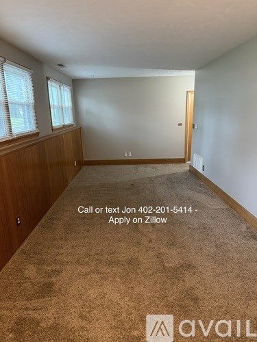 A room with a carpeted floor and a phone number written on it.