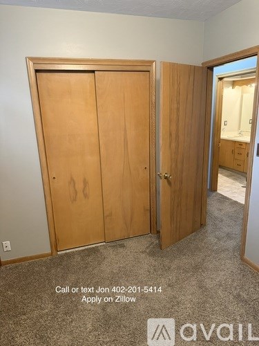 A room with a carpeted floor and two wooden doors.