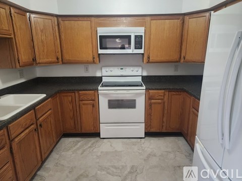 A kitchen with wooden cabinets and a white stove top oven.