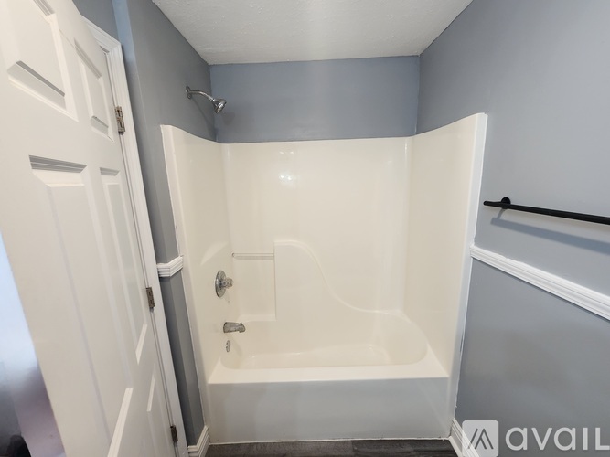 A white bathtub with a shower head and a white door.