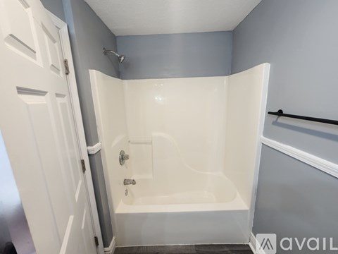 A white bathtub with a shower head and a white door.
