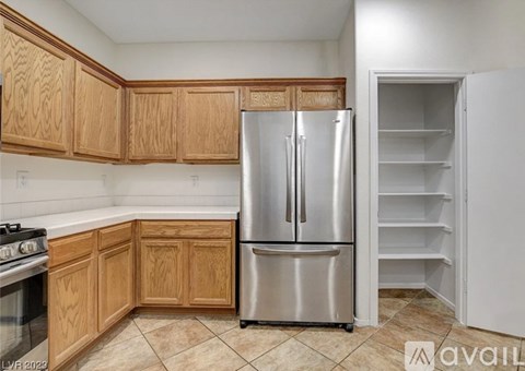 A kitchen with a stainless steel refrigerator and wooden cabinets.