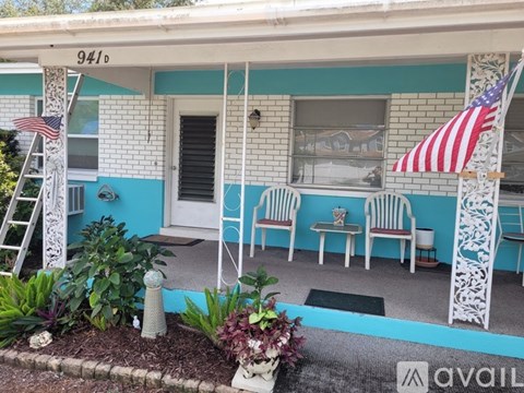 A house with a blue and white exterior and a porch with chairs and an American flag.