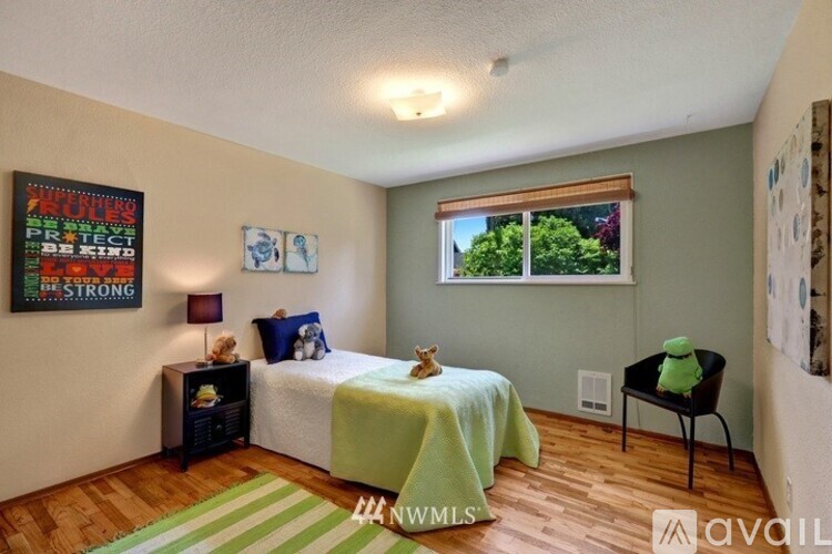 A bedroom with a bed covered in a green blanket and a small table with a green object on it.