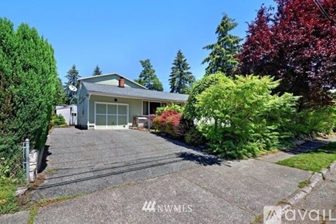 A house with a driveway and trees in front of it.