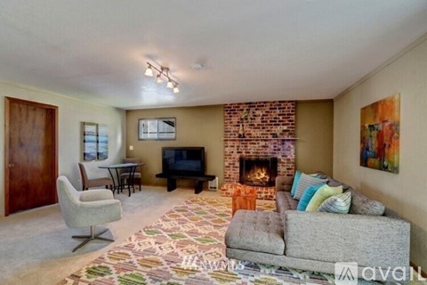 A living room with a grey couch, a fireplace, and a painting on the wall.
