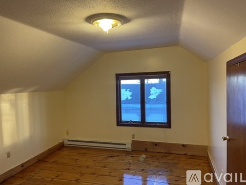 A room with a window and wooden flooring is available for rent.